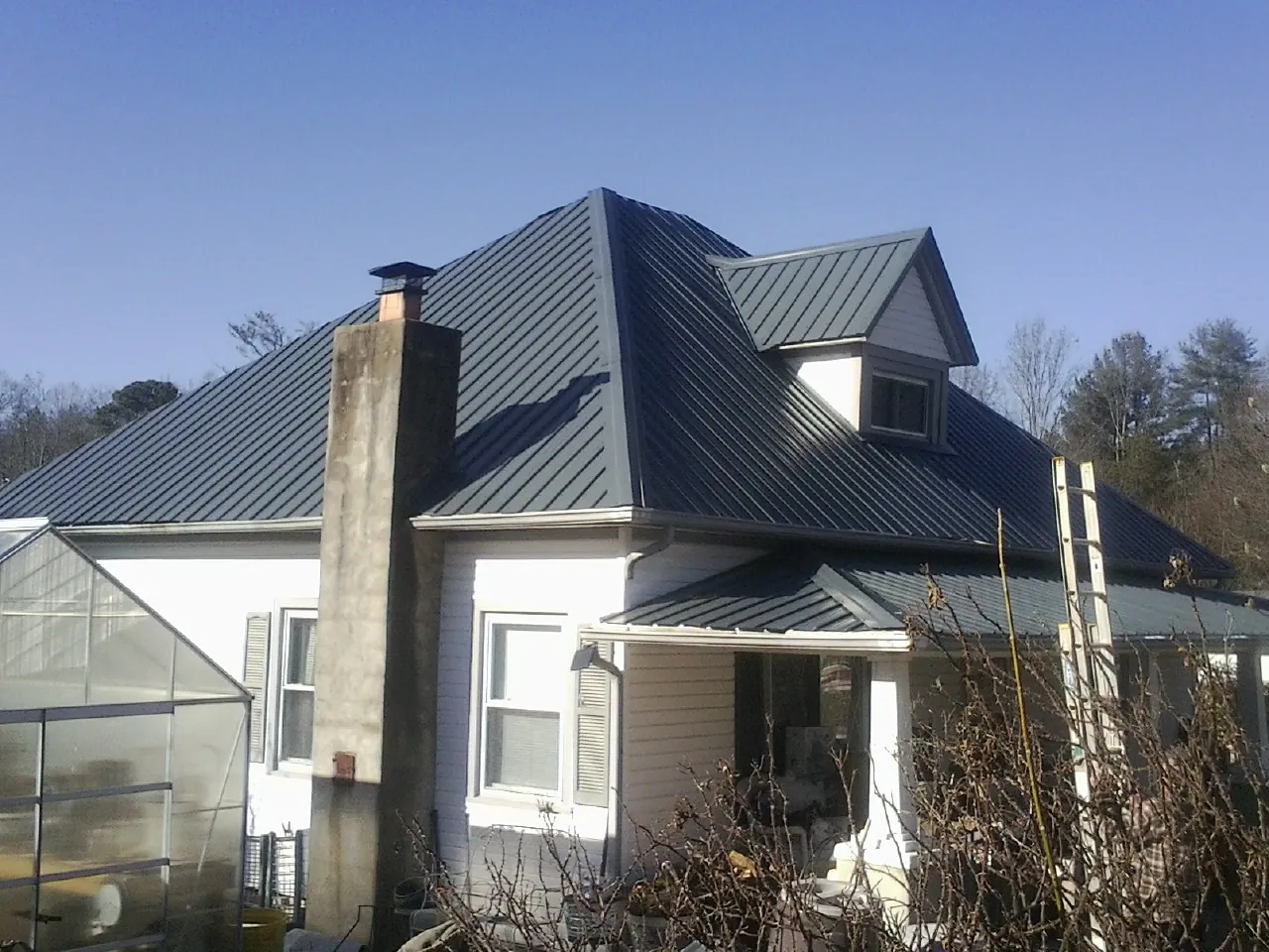 Dark blue standing seam metal roof on a white farmhouse with dormer — Slate & Tile Roof Repair by Roofing Brothers in Peaks Island