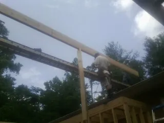 Carpenter setting a ridge beam over a new addition frame — Ice Dam Removal by Roofing Brothers in Peaks Island