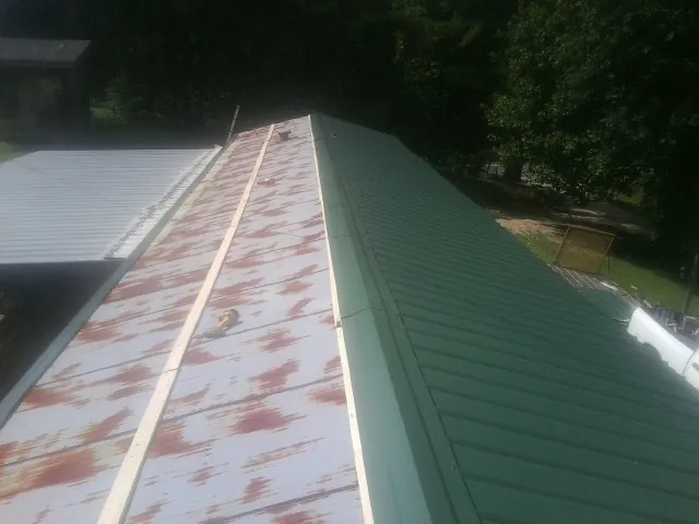 Old rusted panels beside newly installed green metal roofing — Wind Damage Roof Repair by Roofing Brothers in Peaks Island