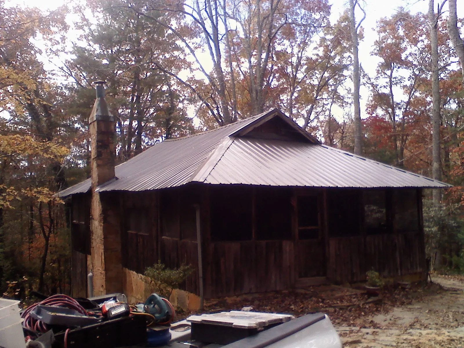 Brown metal hip roof on an old cabin with a stone chimney in Peaks Island