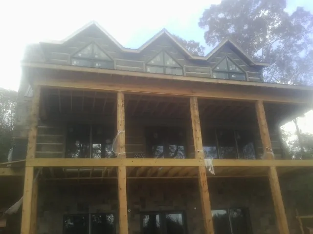 Dormers and porch framing on a large log home under construction — Roof Coating work by our crew in Peaks Island