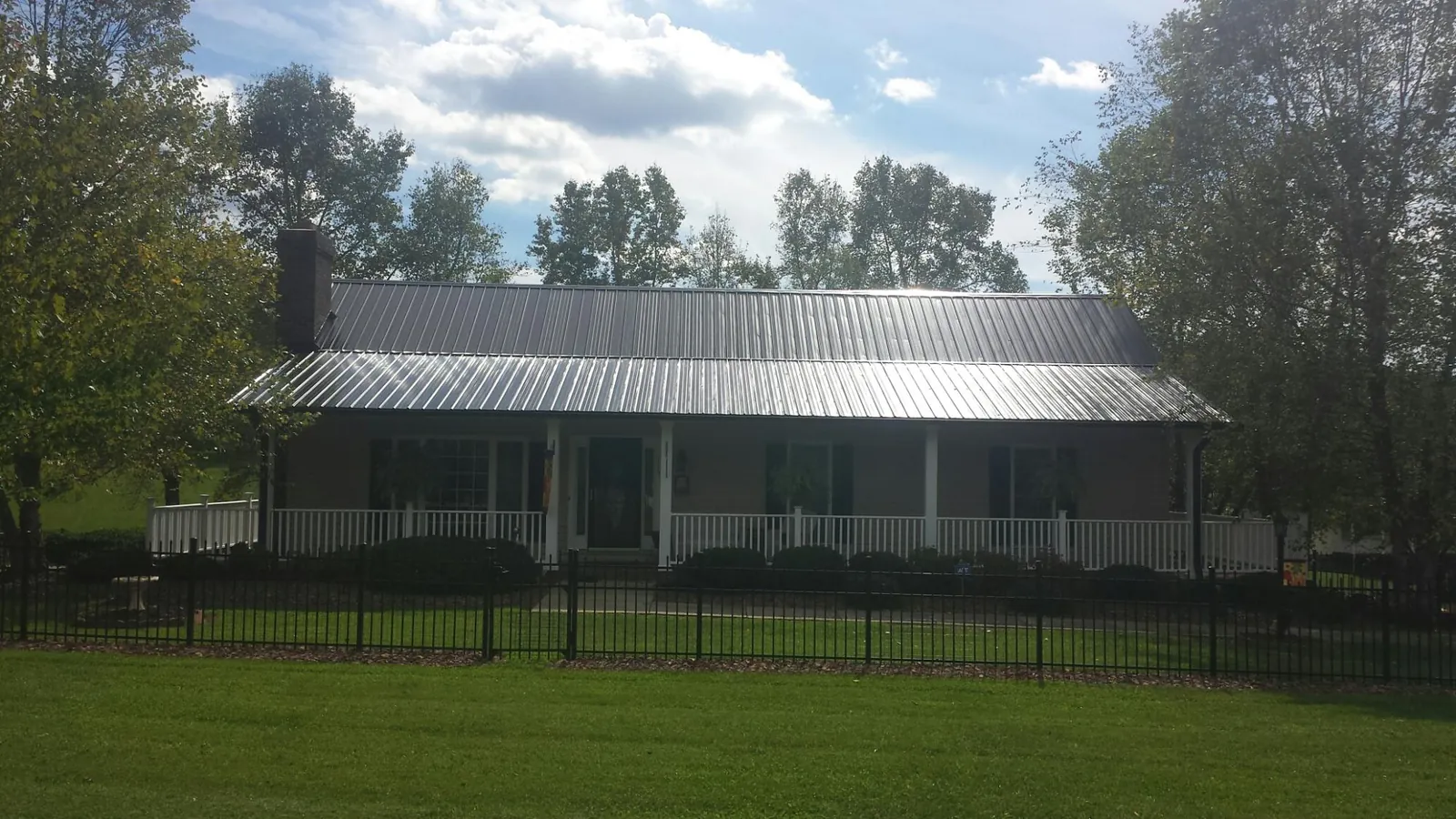 Gray metal roof on a brick ranch with a full width front porch — Gutter Guard Installation work by our crew in Peaks Island