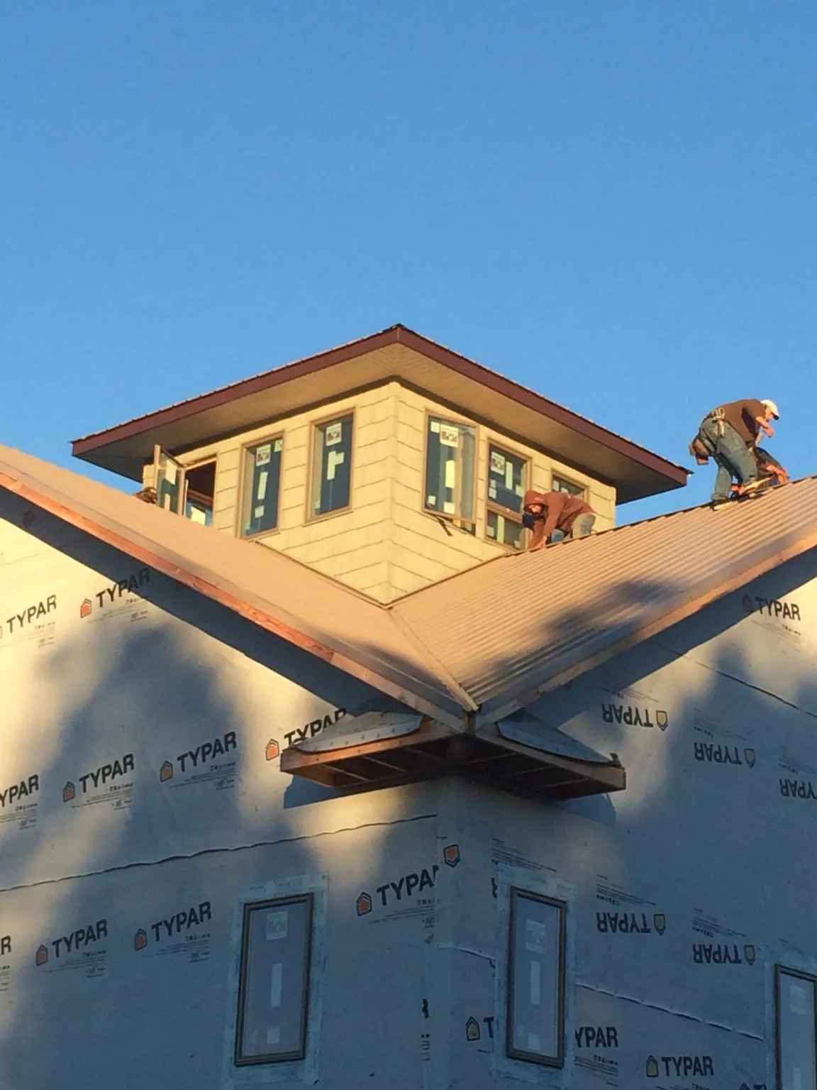 Roofers working around a rooftop cupola on a new metal roof at sunset — Roof Waterproofing in Peaks Island by Roofing Brothers